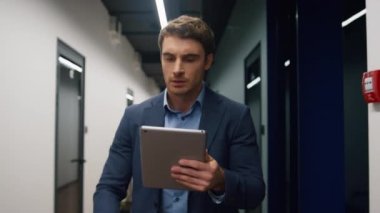 Tablet bilgisayar kullanarak gülümseyen yönetici. Yakışıklı adam iş merkezinde e-posta haberlerini kontrol ediyor. Mutlu yönetici çevrimiçi iletişim daktilo cihazının keyfini çıkarıyor. Şirket çalışanı okuma raporu.