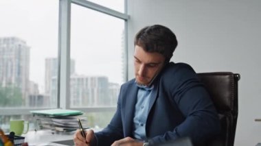 Pazarlama müdürü ofiste cep telefonundan konuşuyor. Meşgul girişimci müşteriye uzaktan danışmanlık belgelerini imzalıyor. Uzaktan kumandalı bir projeyle ilgili profesyonel bir arama yapmak. İşteki kendine güvenen yönetici.