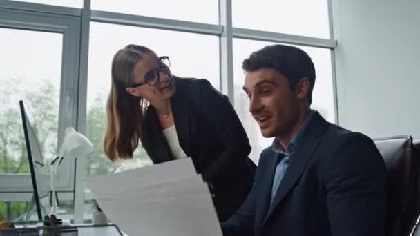 笑顔のオフィスチームは 論文と一緒に動作します 2人の同僚がコンピュータで情報をチェックするプロジェクトについて議論する 職場の従業員を助ける喜びのビジネスウーマンメンター リーダーマネジメントの考え方 — ストック動画