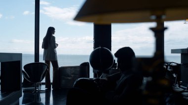 Siluet iş kadını deniz manzarasının tadını çıkarıyor. Bilinmeyen kadın girişimci büyük pencere modern ofisine bakıyor. Şirket çalışanı tek başına yeni bir proje düşünüyor. İş hayatı konsepti