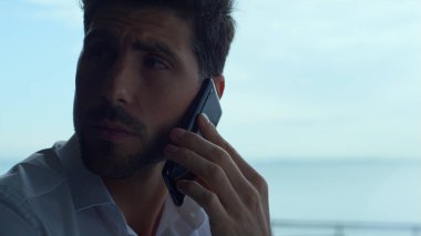 Thoughtful businessman talking smartphone in restaurant portrait. Confident man communicating online using cellphone device closeup. Sad manager having mobile phone negotiations indoors profile.