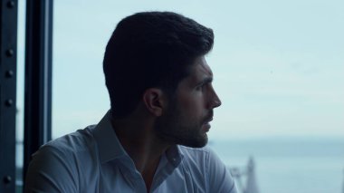 Çekici adam panoramik otel bar portresini rahatlatıyor. Güzel deniz manzaralı düşünceli bir adam restoran profilinde iş görüşmesi için bekliyor. Düşünceli erkek yüz ifadesi yakın plan.