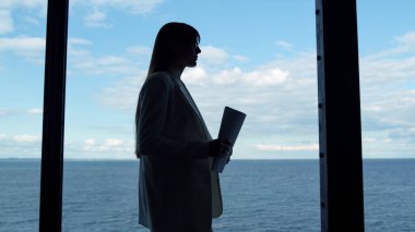 Ofisteki cam odada yönetici silueti. Elinde belgelerle Panorama penceresindeki genel müdürün toplantısına giden kendine güvenen bir iş kadını. Bilinmeyen işçi avukatı deniz manzaralı şirket müşterisini ziyaret etti.