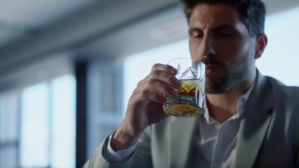 Leader person drinking whiskey in restaurant closeup. Handsome gentleman portrait tasting beverage with unknown colleague in luxury panoramic window cafe. Businesspeople hands holding bourbon glasses
