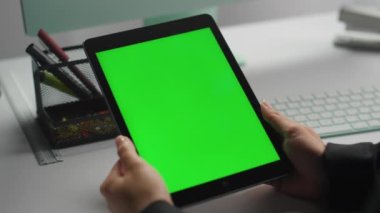 Çağdaş iş yerinde eller yeşil tableti yakın mesafeden tutar. Freelancer, işten sonra dinlenme platformunu izlemek için krom anahtar kullanıyor. Bilinmeyen yönetici kurumsal sanal toplantı hakkında konuşuyor