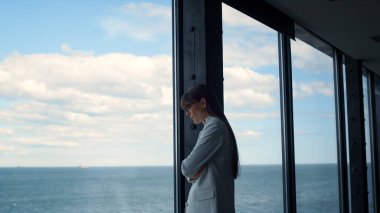 Panorama penceresindeki sorunları düşünen bir kadın. Odaklanmış yönetici, çözüm fikirlerini ofiste tek başına inceler. Depresyondaki başarılı iş kadını deniz manzarasında karar veriyor. Düşünceli esmer bayan.