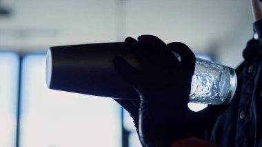 Bartender hands shaking cocktails closeup. Unknown barman mixing ingredients for alcohol drinks in shaker indoors. Unrecognizable person with cobbler in bar. Process of making beverage in restaurant