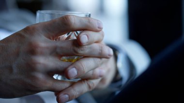 Gentleman hands drinking whiskey in restaurant closeup. Unrecognizable businessman tasting beverage in luxury hotel room. Ceo relaxing enjoying bourbon in office. Unknown man spending vacation