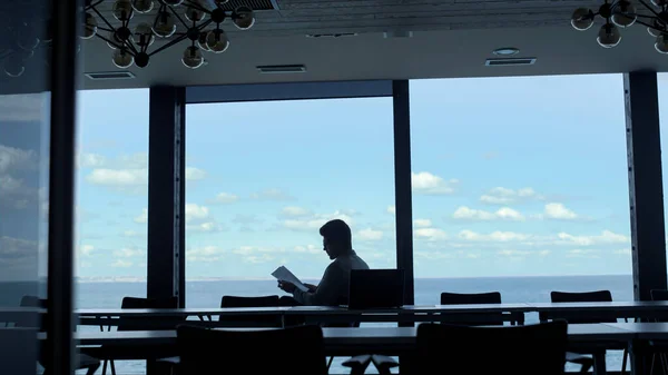 Leader person reading papers at ocean view. Office manager checking documents at luxury hotel. Unknown businessman holding company report at panoramic window. Anonymous investor analyzing deal concept