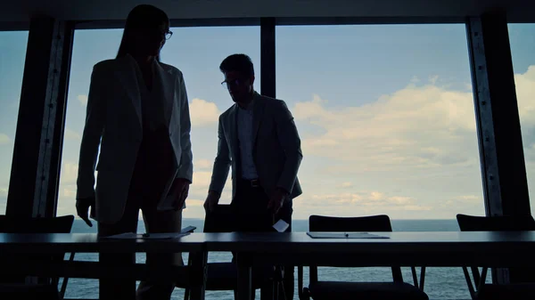 Business silhouettes shaking hands meeting in conference room. Two managers work on company agreement. Unrecognized ceo attorney greeting client investor at panorama window. Successful deal concept