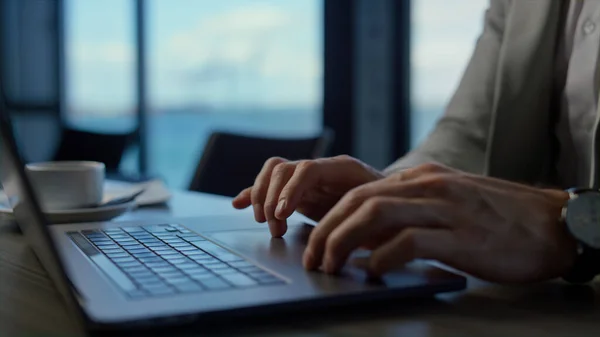 Unrecognizable businessman work laptop at sea office closeup. Man employee hands typing notebook keyboard slow motion. Unknown director scrolling fingers touchpad at panoramic window view place