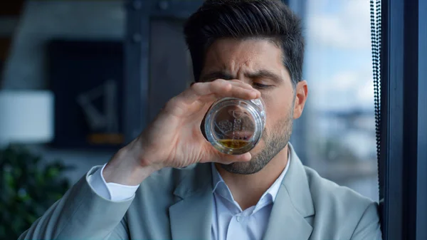 Rich man tasting cognac in luxury interior portrait. Confident gentleman enjoying vacation with whiskey glass. Intelligent businessman relaxing alone with alcohol drink looking through big window