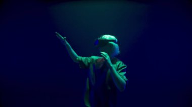 Sanal gerçeklik oyuncusu neon ışıklarla oynuyor. Görünmez nesnelere dokunarak simülasyonu keşfeden sarışın adam. Tanınmayan sarışın ergen metaverse oyunu yaşıyor. Moda haftasonu eğlencesi.