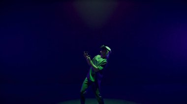 Excited player enjoying vr game in neon lights room. Futuristic man playing using headset controllers in augmented reality. Unrecognized gamer exploring metaverse simulation. Trendy innovation concept