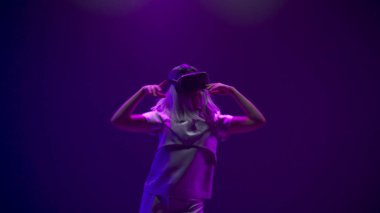 Involved girl visit virtual party closeup. Modern woman immersed in abstract neon vr world. Young person augmented reality headset dancing alone slow motion. Metaverse technology future concept