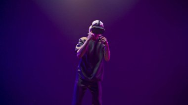 Focused teenager fighting invisible opponent in digital metaverse world. VR goggles man having fun play boxing in sport game futuristic neon colourful background. Technologies and entertainment 