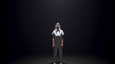 Gelecekçi kız karanlık odayı aydınlatacak. Gri elbiseli, gümüş saçlı güzel bir hippi. Siyah arka plana bakan çekici genç siber oyuncu. Şehir dansçısı genç yaşam tarzı 