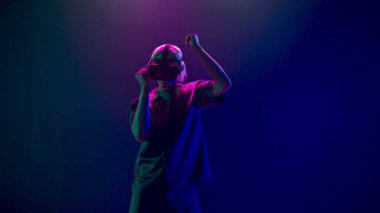 Addicted man gaming moving in invisible space using VR. Young blonde person virtual reality goggles dancing in colourful neon metaverse slow motion. Future technology for entertainment concept 