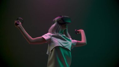 Excited woman experiencing handheld trackpads videogame closeup. Impressed gamer using gadget for virtual reality on neon background. Futuristic goggles youngster playing. Future technology concept