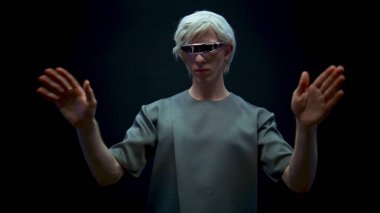 VR gözlüklü adam yakın plan oyun oynuyor. Meta-evren simülasyonunda odaklanmış genç alışverişi. Geleceğin sarışın adamı karanlık siber uzayda el kol hareketi yapıyor. Gelecekteki teknoloji gerçeklik aygıtı.