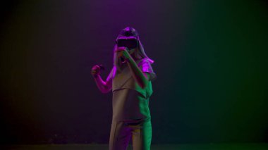 VR goggles girl gaming fighting alone. Skilled woman playing immersive virtual reality game using controllers slow motion. Blonde person enjoying 3D technology. People and metaverse concept 