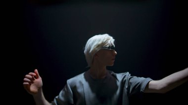 Gamer wearing virtual goggles in futuristic light. Focused man touching air in dark room. Blonde guy swiping interface immerse augmented reality in headset. Teenager enjoying trendy console simulation