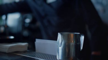 Barista müşteriye yakın çekim için kahve servisi yapıyor. Bar tezgahına tabak kaşık koyan tanınmamış profesyonel barmen kol eldivenleri. İsimsiz bir adam, karanlık lüks restoranda sıcak aromatik espresso yaptı.
