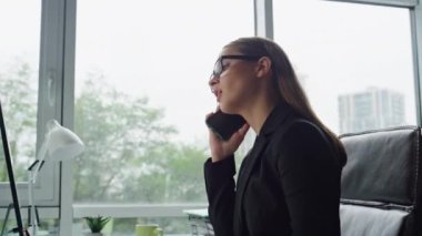 Ofiste profesyonel bir kadın yakın çekim yapıyor. Odaklanmış CEO iş kadını cep telefonu danışmanlığı finans ortağı ile uzaktan konuşuyor. Başarılı yönetici serbest çalışan işyerinde akıllı telefonlardan konuşur.