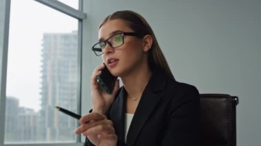 Kadın yönetici ofiste akıllı telefondan konuşuyor. Yakın plan. İş ortağıyla pazarlama projesini tartışan odaklı yönetici danışmanı. Güzel iş kadını iş yerinden çağrı yapıyor.