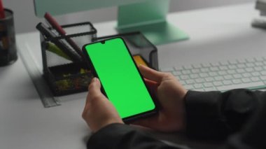 Ofisteki yeşil akıllı telefonu yakın plan çekimde tut. İşadamı Chroma Key Cihazı 'ndan gelen mesajları kontrol ediyor. Akıllı kontrol uygulaması kullanan tanınmamış bir çalışan. İşçi sanal çağrı konuşuyor.