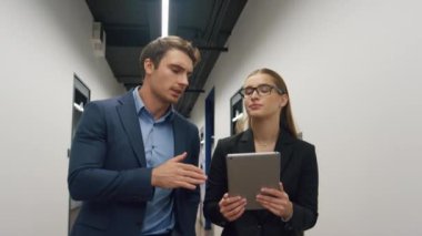 Ofis danışmanı stajyer raporunu kontrol ediyor. Tablet bilgisayarında odaklanmış iş adamları koridor analizi yapıyor. Yöneticiye verileri açıklayan üzgün kadın asistan. Profesyoneller birlikte çalışır..