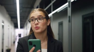 Gülümseyen iş kadını video görüşmesini yakından konuşuyor. Serbest çalışanın ofis merkezine gidip online konferans düzenlediği için mutlu. Güzel bir kız iletişim kurarken akıllı telefon kullanır. Şirket yaşam tarzı kavramı