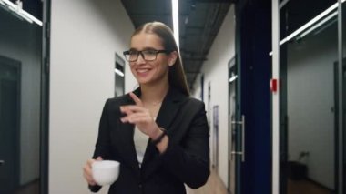 İş kadını öğle yemeği molasında ofiste yürüyor. Gülümseyen menajer sabahki müşteri toplantısına gidiyor. Başarılı yönetici iş arkadaşlarını kahve içerken karşıladı. İyi çalışanlar dinlenin..