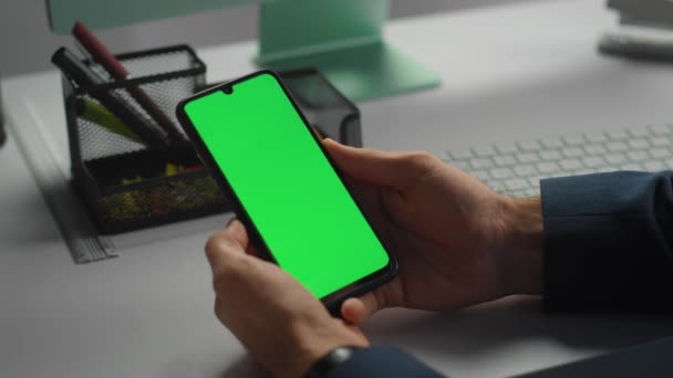 手牵着绿色智能手机特写 办公室职员上网查阅股票市场数据 未被认可的企业管理者在工作场所使用彩色密钥移动电话 Gadget模拟概念 — 图库视频影像