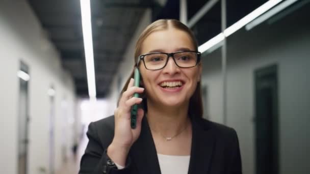 陽気な女性の携帯電話を閉じる話 美しいマネージャーは 現代のオフィスで成功したニュースを共有するパートナーを話す 会話の廊下を楽しむ幸せな実業家のアシスタント — ストック動画