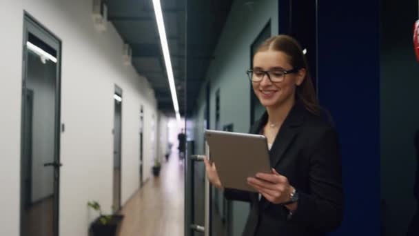 タブレットウォーキングオフィスホールに触れる笑顔ビジネス女性 成功した結果をオンラインで点検するコンピュータを使用して幸せなCeoの専門家 魅力的なフリーランスの若い弁護士が廊下に行く電子メールを送る — ストック動画
