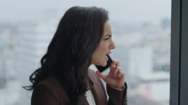 Sinirli iş kadını telefonda tartışıyor duygusal olarak ofis penceresinde dikiliyor. Yönetici kız, şirket anlaşmasında hayal kırıklığı yaratan mobil hata diye bağırıyor..
