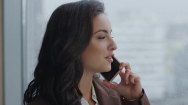 Esmer kadın yönetmenin ofis penceresinde şık takım elbiseli bir iş görüşmesi var. Gülümseyen şirket CEO 'su akıllı telefon kullanarak güzel bir telefon görüşmesi yapar. Bayan ortaklarla konuşuyor.