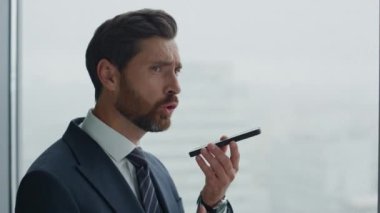 Yakın plan sakallı iş adamı hoparlörden sesli mesaj kaydediyor. Sinirli duygusal stres yöneticisi cep telefonu mikrofonunda yüksek sesle konuşuyor. Patron ses bildirimi dikte ediyor.