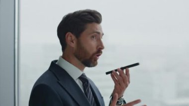 Öfkeli orta yaşlı yönetici akıllı telefonu arıyor duygusal olarak ofis penceresinin önünde duruyor. Stresli iş adamı memnun olmayan şirket işi. Cep telefonu kullanan sakallı girişimci.