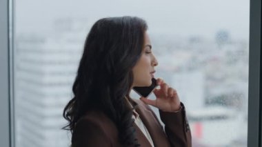 Ofis penceresinin önünde akıllı telefon düzenleme toplantısını kullanan kendine güveni tam bir iş kadını. Çekici kız CEO 'nun portresi müşterilere telefonda danışıyor. İş kadını telefonda konuşuyor..