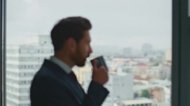 Zengin, kendine güvenen girişimci kahve molası veriyor. Lüks ofis penceresinden şehir manzarasına bakıyor. Düşünceli CEO 'nun portresi tek başına içki içip iş kariyerini düşünmek..