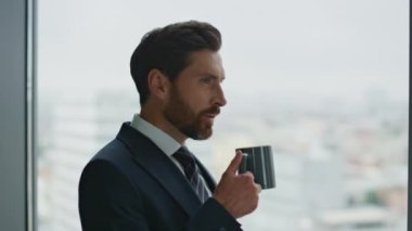 Cazibeli sakallı iş adamı kahve molasında ilham alıyor. Şehir manzarasında ofis penceresine bakıyor. Kendine güvenen yönetici portresi yeni fikir çözümleme sorunları yaratıyor..