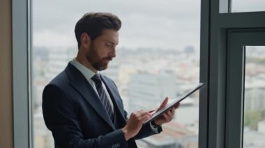 Mutlu sakallı işadamı ofis penceresinde tek başına kârlı bir anlaşma imzalıyor. Finansal belgeleri analiz ederken başarılı bir CEO 'ydum. Gülümseyen adam kitap sözleşmesi