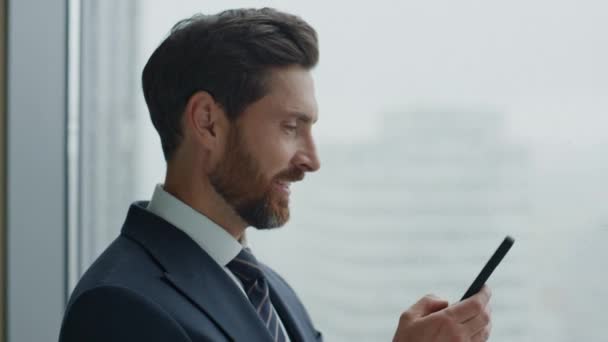 Χαρούμενος Διευθυντής Γραφείου Χρησιμοποιεί Smartphone Στέλνοντας Μήνυμα Κοντά Στο Παράθυρο — Αρχείο Βίντεο