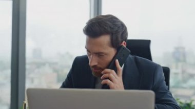 Ofiste konuşan sakallı çekici bir danışman. Laptop ekranına yakından bakıyor. Telefon oturma masası aracılığıyla müşterilere danışmakla meşgul zarif bir yönetici. İş adamı konuşuyor.