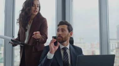 Çekici kadın patron dizüstü bilgisayarda oturan modern ofis çalışanına talimat veriyor. Esmer iş kadını yönetici iş belgelerine kitap okuyor. Takım çalışması ortaklık kavramı.