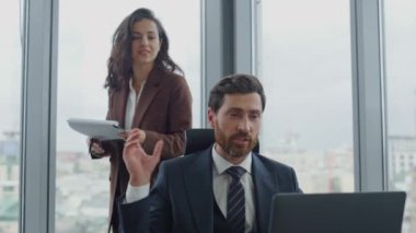 Çekici kadın asistan, CEO 'nun belgeleri okumasına yardım ediyor. Lüks şirket ofisinde birlikte çalışan kendine güvenen iki iş arkadaşı. Yönetici dizüstü bilgisayarla oturuyor.