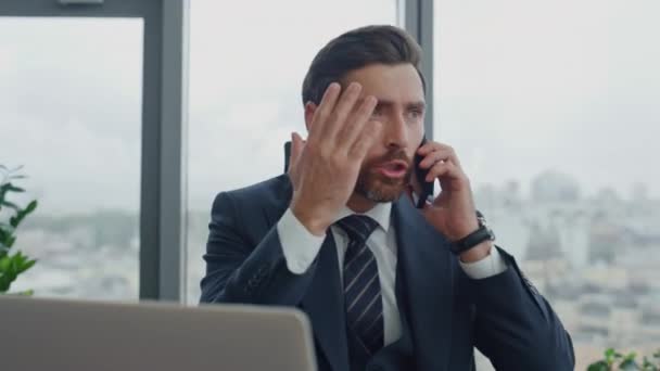 仕事机の近くの高級事務所に座って電話をかける怒っている心配のビジネスマン 電話会話の会社の問題を議論する神経質なひげそりのエグゼクティブマネージャー ストレスを感じる男労働者 — ストック動画