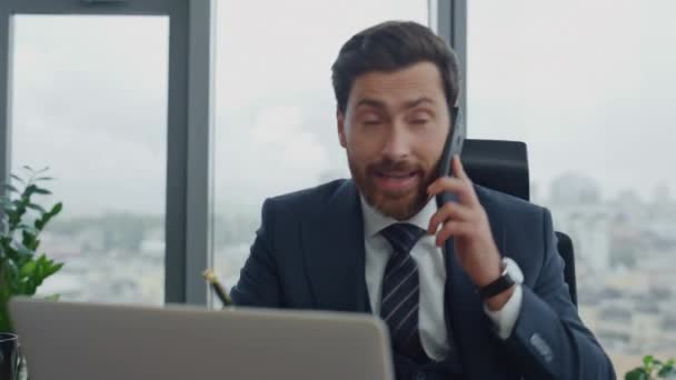 精明的财务经理坐在豪华的办公室附近 通过电话进行咨询 迷人的留胡子商人在笔记本上讲智能手机写作信息 有信心的人在讲电话 — 图库视频影像